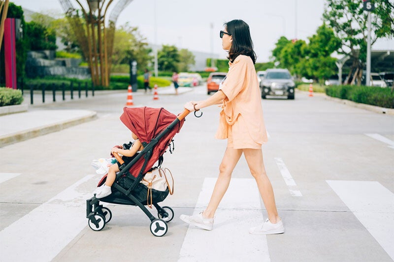 A father pushing baby in stroller while bringing travel essentials in backpack.