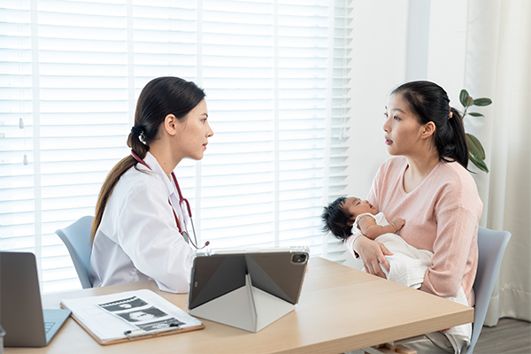 A female Asian doctor and mom with her newborn, discussing newborn hiccups