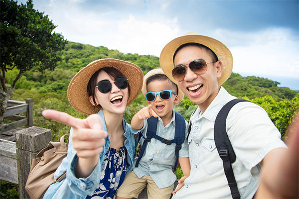 A happy Asian family on a hiking adventure and taking a selfie.