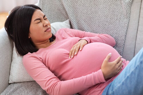 A pregnant Asian woman lying on the sofa, experiencing Braxton Hicks