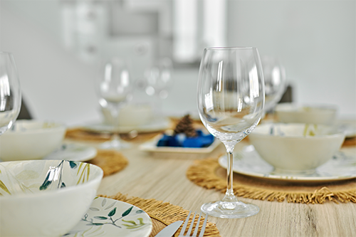 A table laid out with patterned plates, bowls, and wine glasses