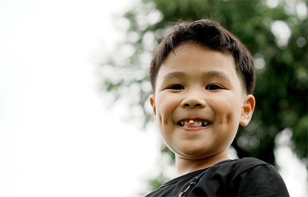 A young Asian boy with a loose front tooth.
