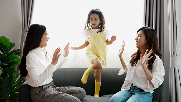 A young Asian girl is practicing dancing with her sister and mom