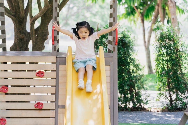 A young Asian girl playing on the slide in the playground