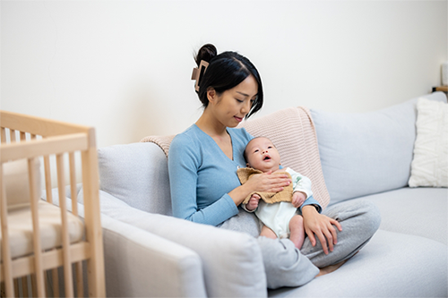 A young Asian mom gently holding her baby upright, which helps with colic in babies