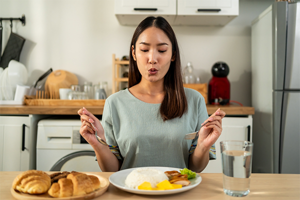 A young Asian woman eating a delicious meal at home to fuel her breastfeeding