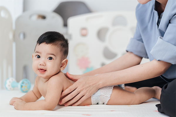 Adorable Asian baby gets a back massage from his mom
