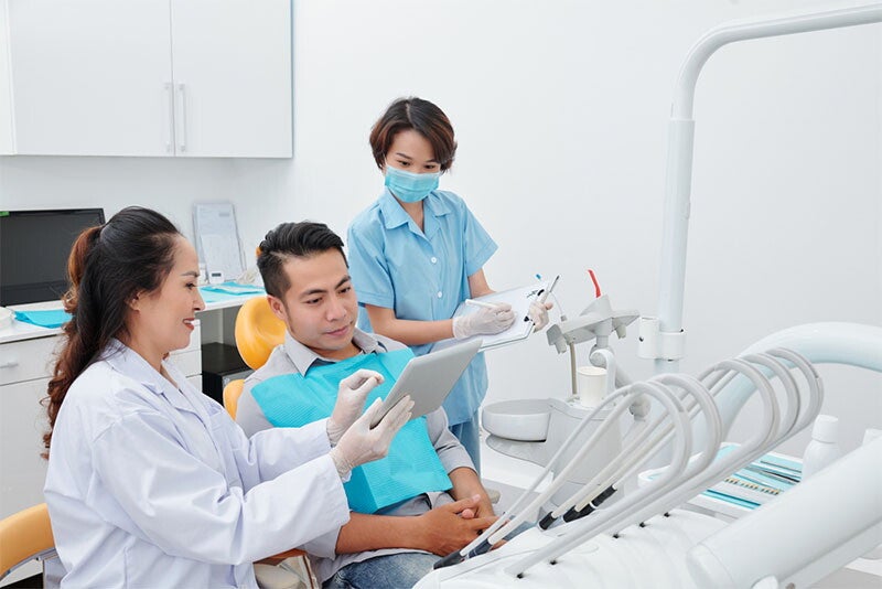 An Asian female dentist showing a teeth x-ray to a young Asian male patient