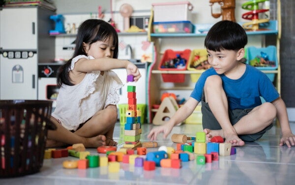 An Asian little girl and boy playing wit toys together.