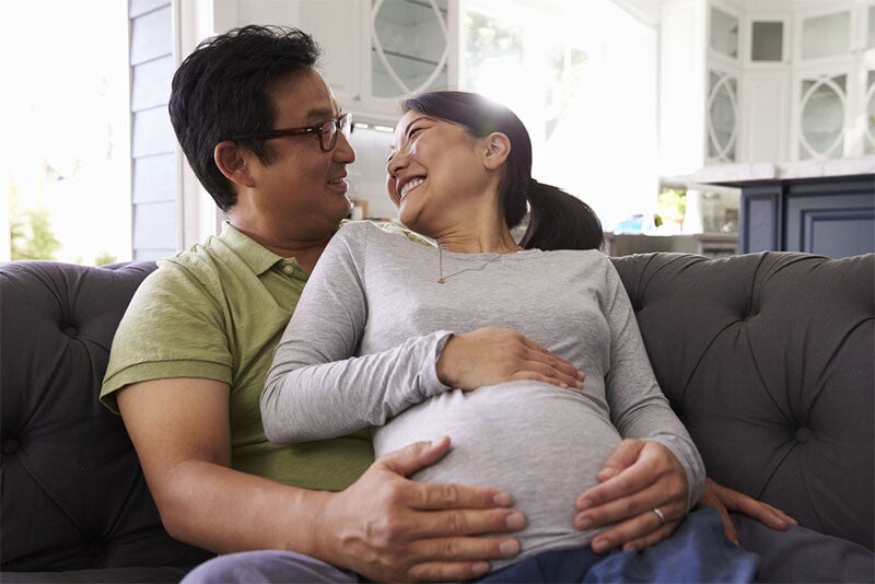 An expectant couple relaxing on sofa at home together