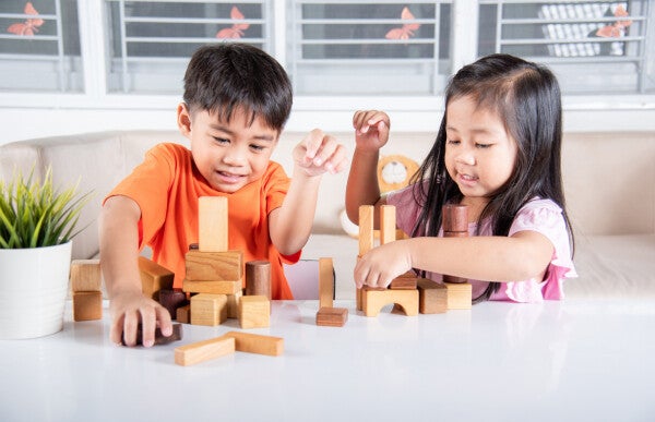 Asian boy and girl playing with blocks indoors.