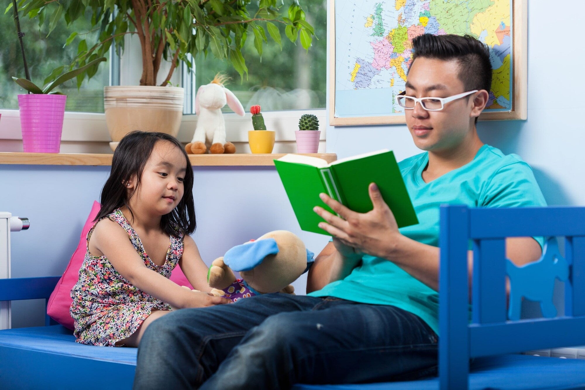 Asian dad spends quality time, one of the five kinds of love language, by reading to his daughter.  
