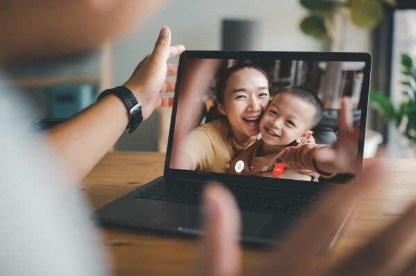 Man talking on his laptop with his smiling wife and son