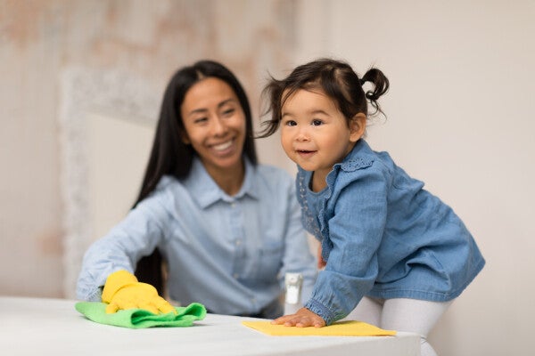 : Asian mother and child wiping a table down, doing household chores for kids.