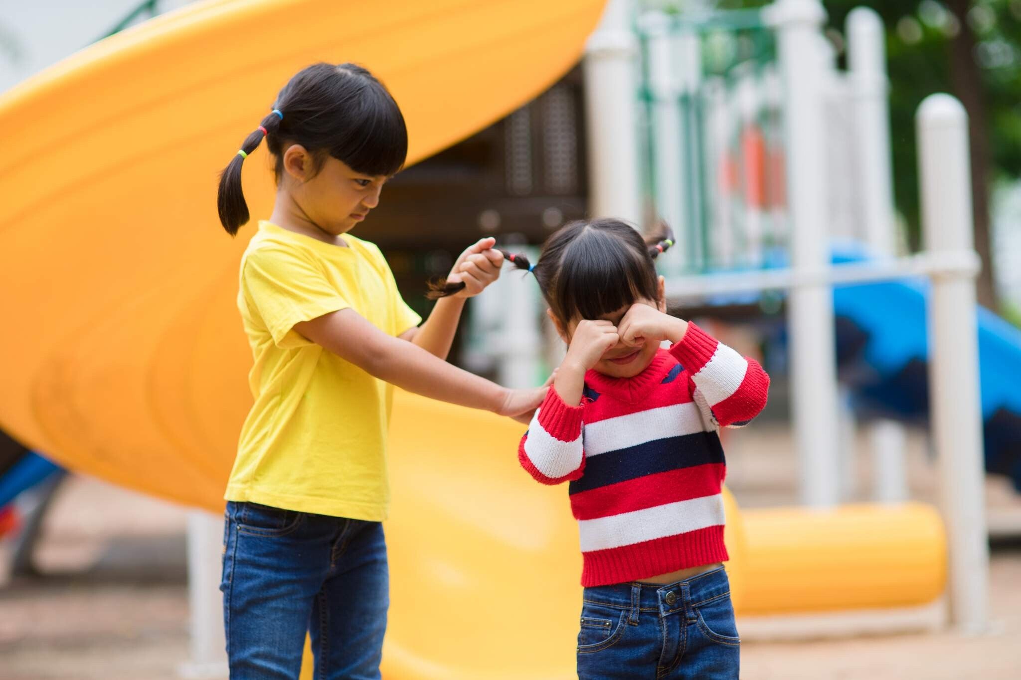 Asian sisters fighting and pulling hair in playground.