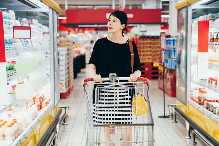 Young Asian woman looking for safe yogurt for pregnant moms in the grocery.