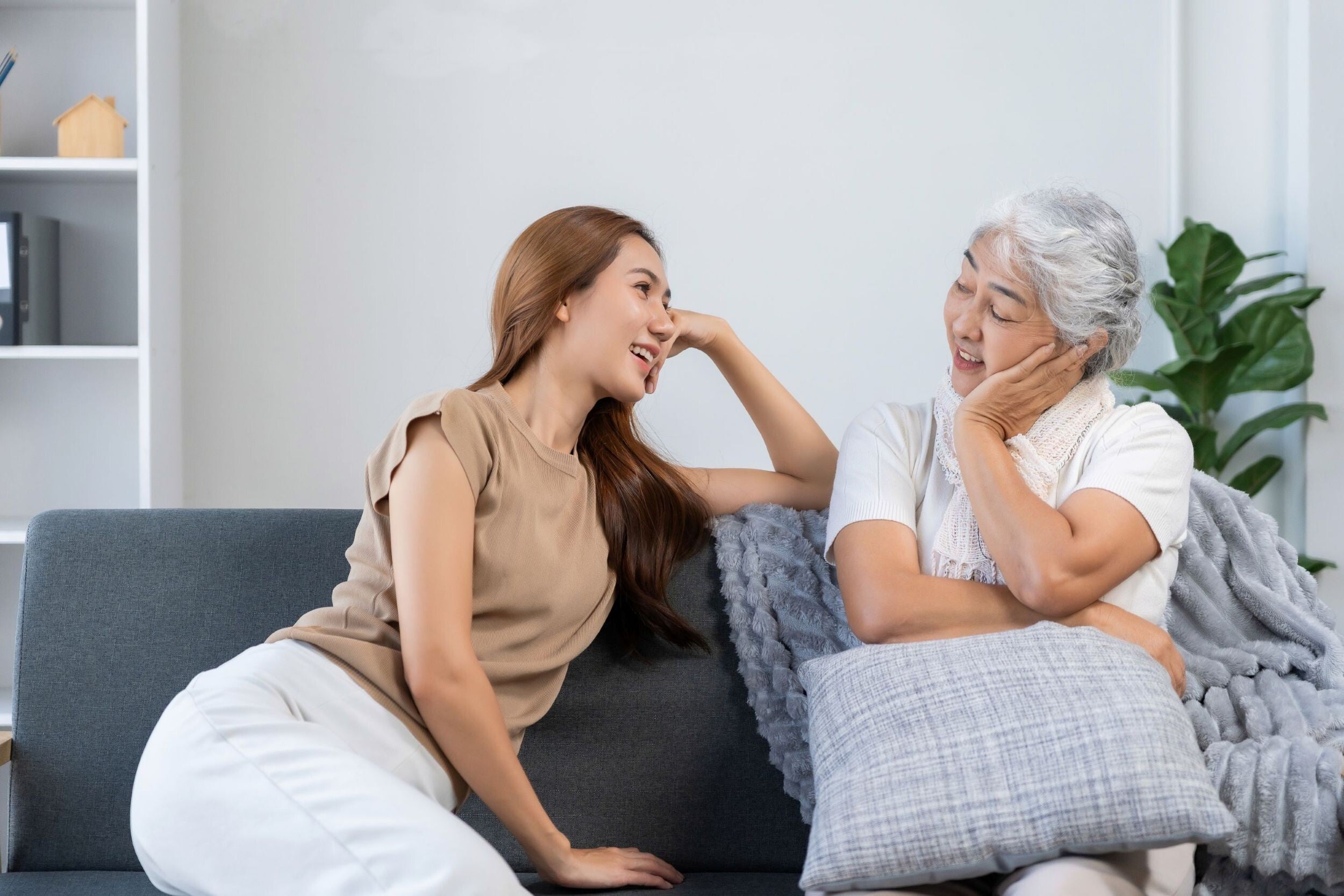 Asian woman talking to her mom on the sofa in their living room.