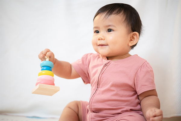 Asian 1-year-old baby shows a strong grip as they hold a stacking toy