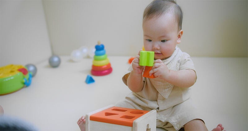 Asian baby plays a shape sorter, a Montessori toy