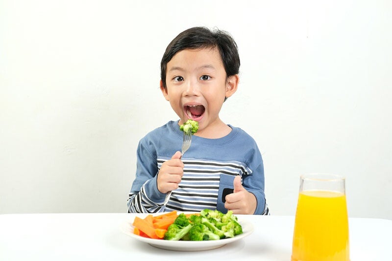 Asian boy eating a balanced meal of vegetables