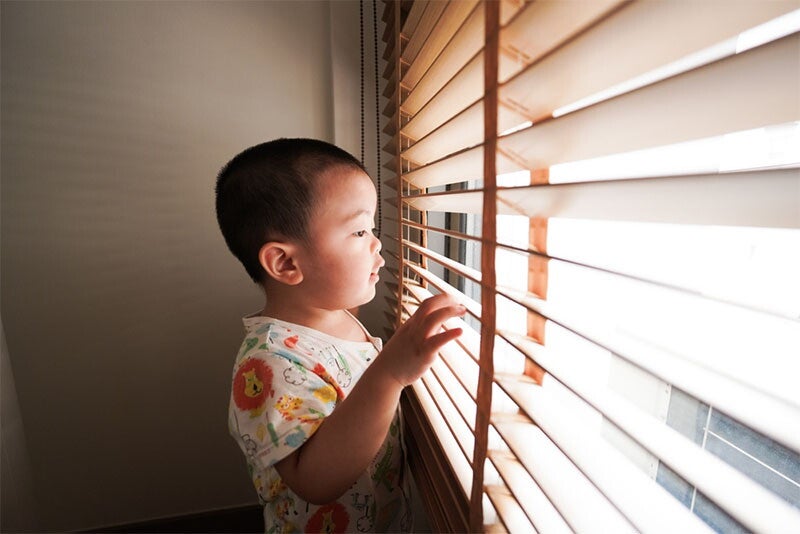Asian boy peeking through blinds