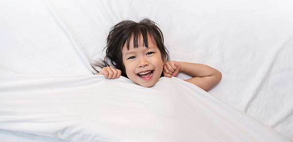 Asian child wakes up smiling while still in bed.