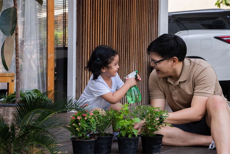 Asian dad and daughter tending to a garden at home for some family bonding