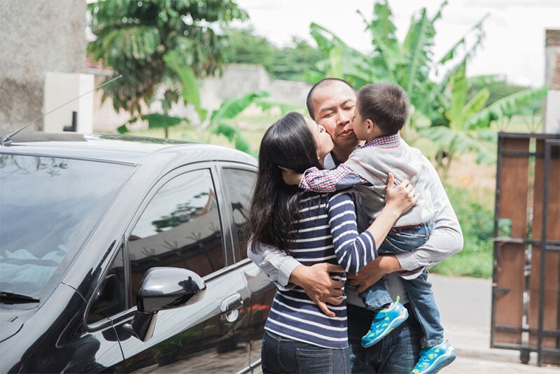 Asian dad arrives home and gets greeted by kisses on the cheeks from his wife and son