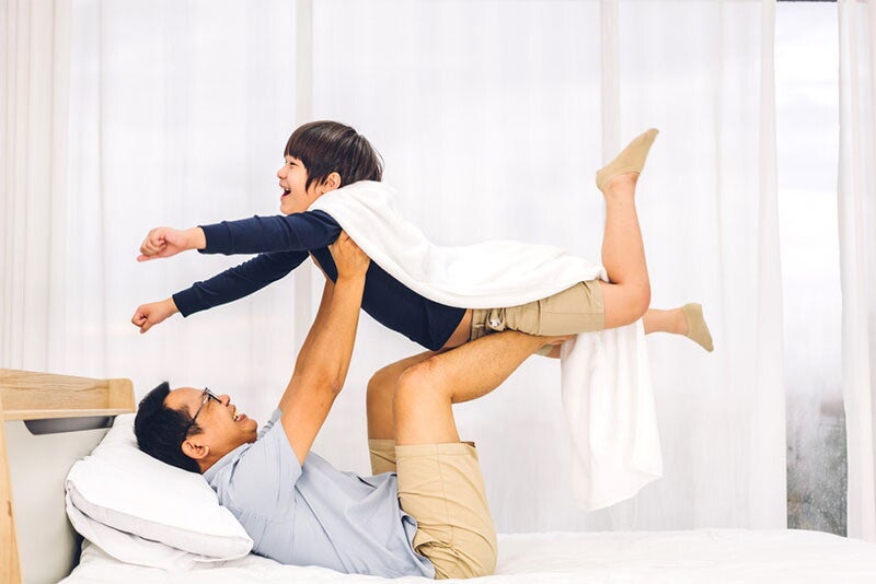 Asian dad playing airplane with son