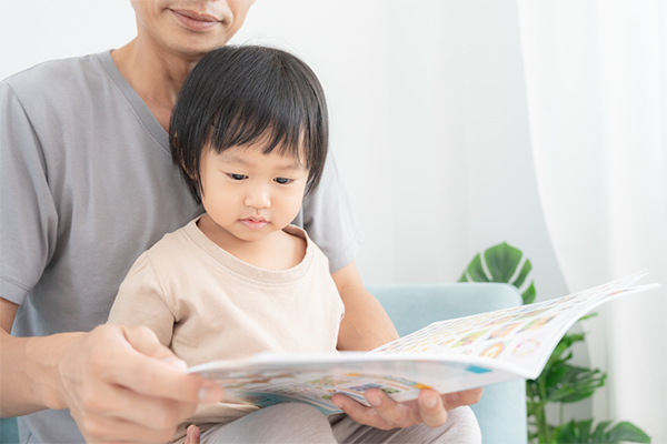 Asian dad reads a book to his toddler to teach them about feelings