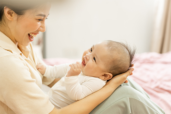 Asian mom and baby smile at each other during a brain game