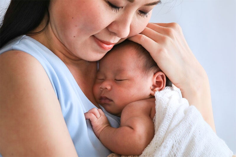 Asian mom embraces her newborn
