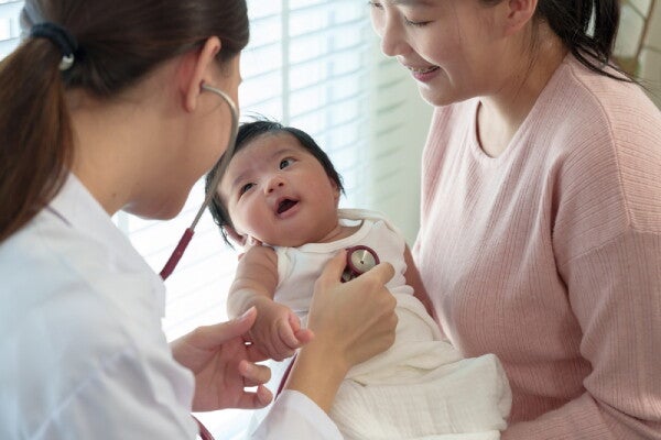 Asian mom holds her newborn during a pediatrician checkup