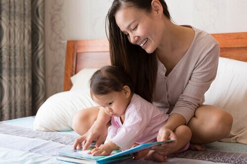 Asian mom reading a mythology book to her little girl in bed