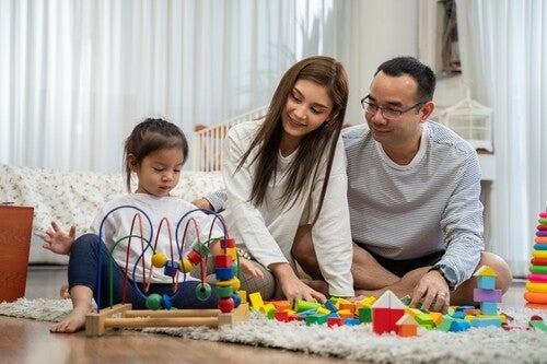 Asian parents playing with their little girl in the living room during the rainy season