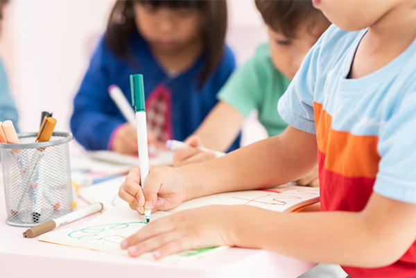 Asian preschool-aged children draw shapes during kindergarten class