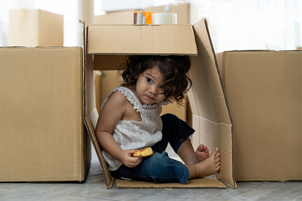 Asian toddler plays hide and seek inside her cardboard fortress