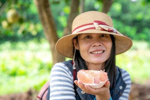 Asian woman eating an open pomelo