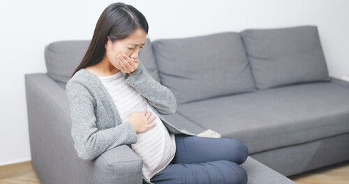 Asian woman on a sofa feeling nauseated during early pregnancy