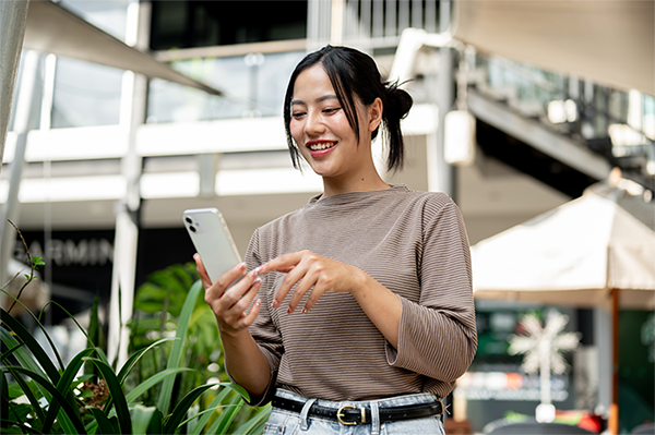 Asian woman texting on her smartphone with a smile on her face