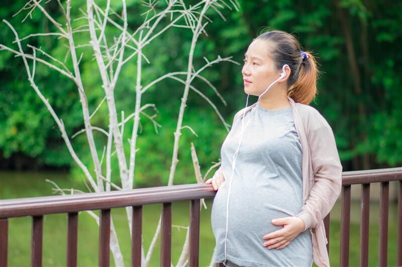 Asian woman wearing earphones and doing examples of light exercises like walking.