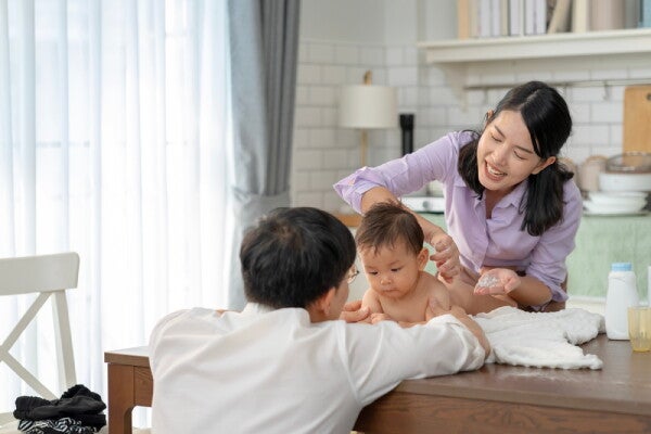 Asian working parents conducts post-bath routine on their baby who's on the dining table.