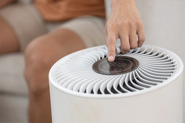 Close-up of a hand pressing a button on the air purifier