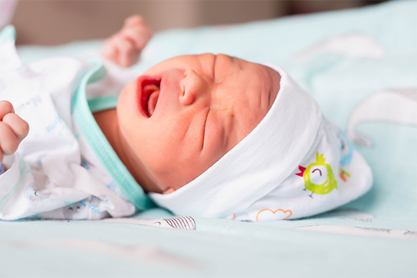 Close-up photo of a startled Asian newborn clenching their fists.