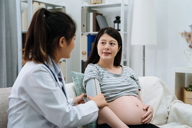 Close-up photo of doctor’s hands monitoring the blood pressure of a pregnant woman with a digital equipment.