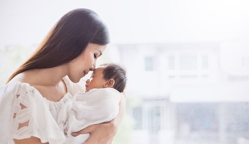 Closeup portrait of a beautiful young Asian mother day kissing her newborn baby.