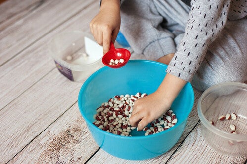 Cropped photo of a little boy scooping and pouring dried beans into different containers