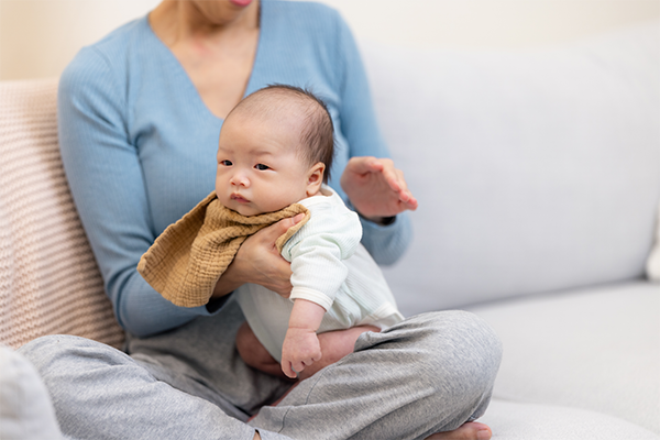 Cropped photo of an Asian mom burping her baby to help prevent newborn hiccups