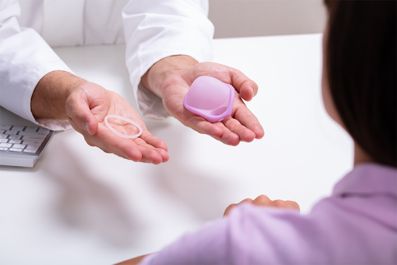 Gynecologist showing contraception ring and diaphragm to woman and explaining contraception and birth control methods