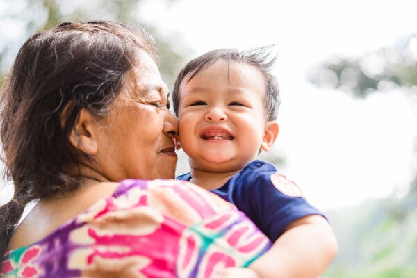 Asian grandmother nuzzles her grandson's cheek with her nose much to his delight.